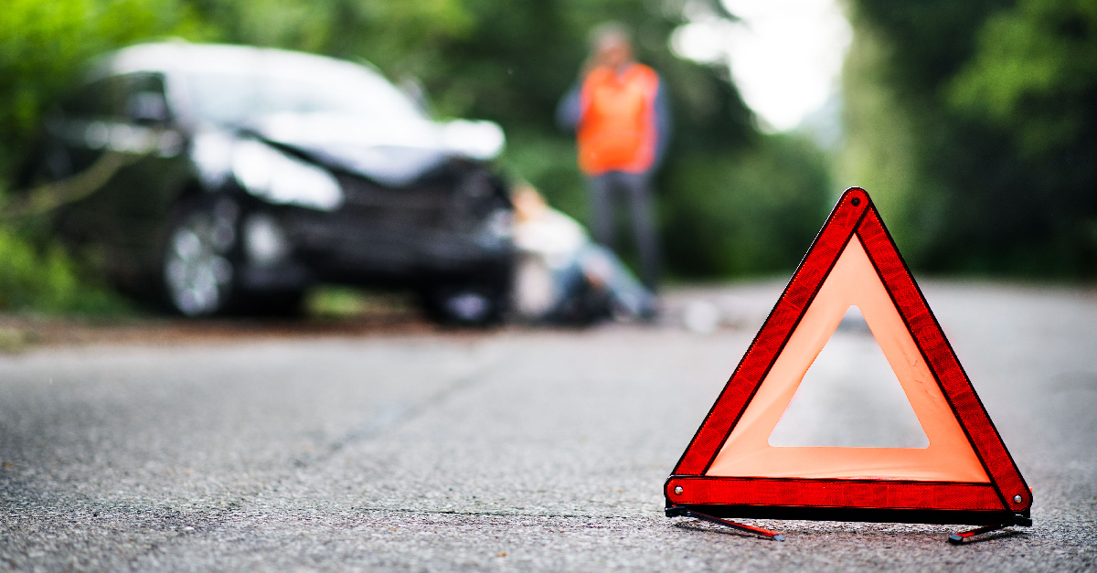 an image of a car that has been in a car crash with a triangular road warning sign in the foreground