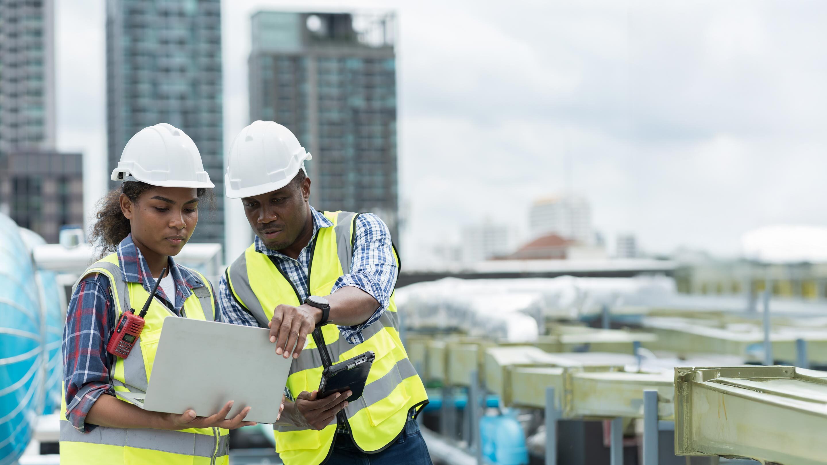 two people in construction clothing looking at a laptop