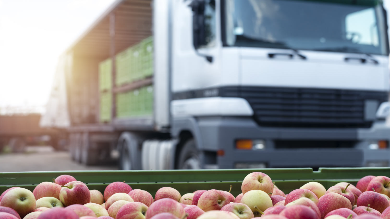 A bunchof apples in a basket infront of a truck