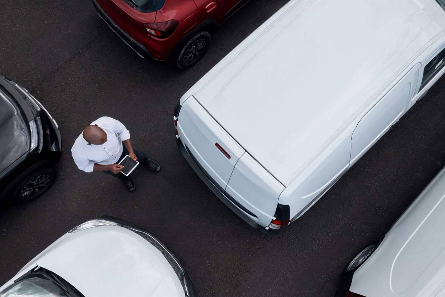 person with a tablet walking between vehicles