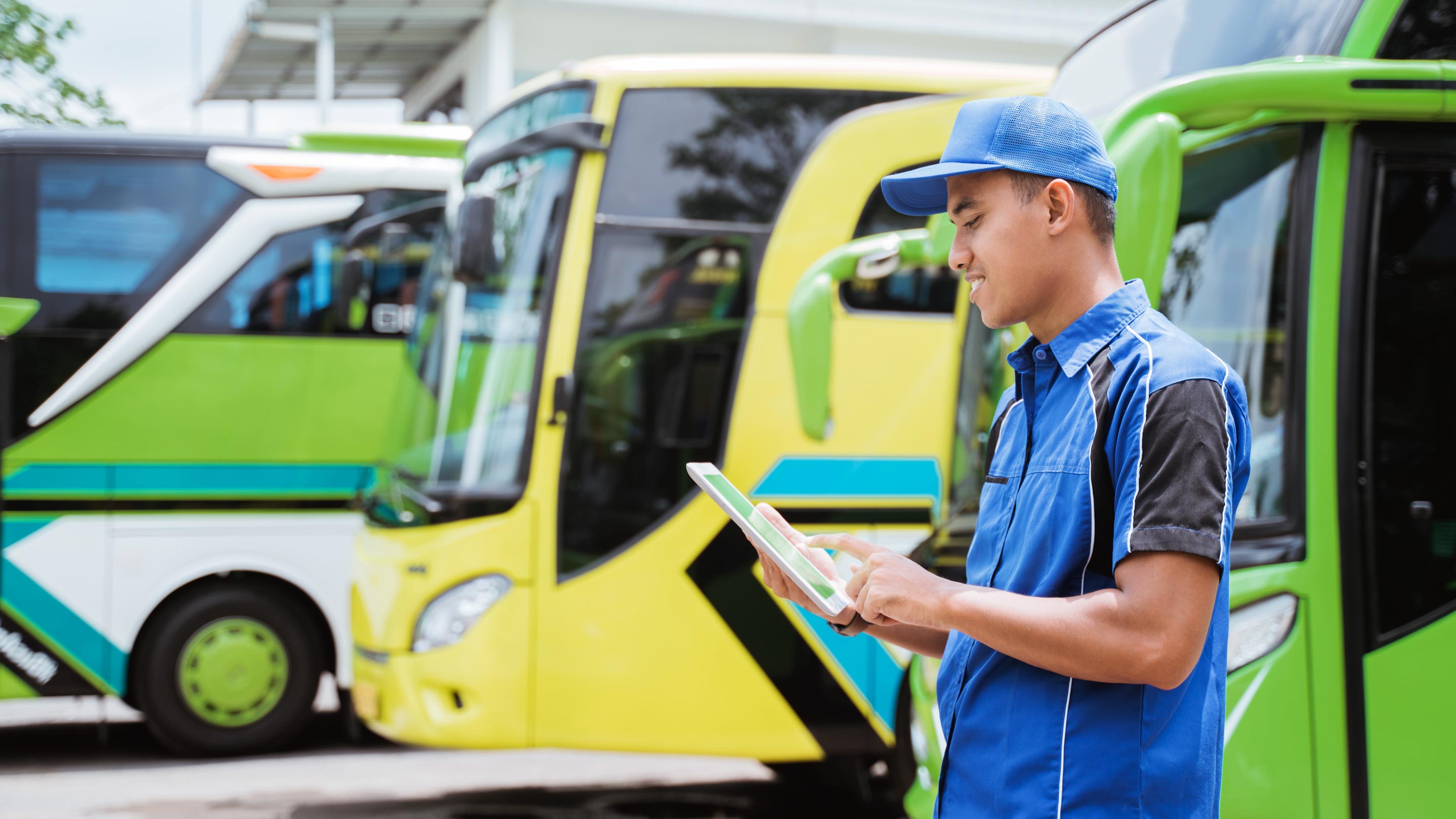 Hombre usando una tableta con autobuses aparcados en el fondo