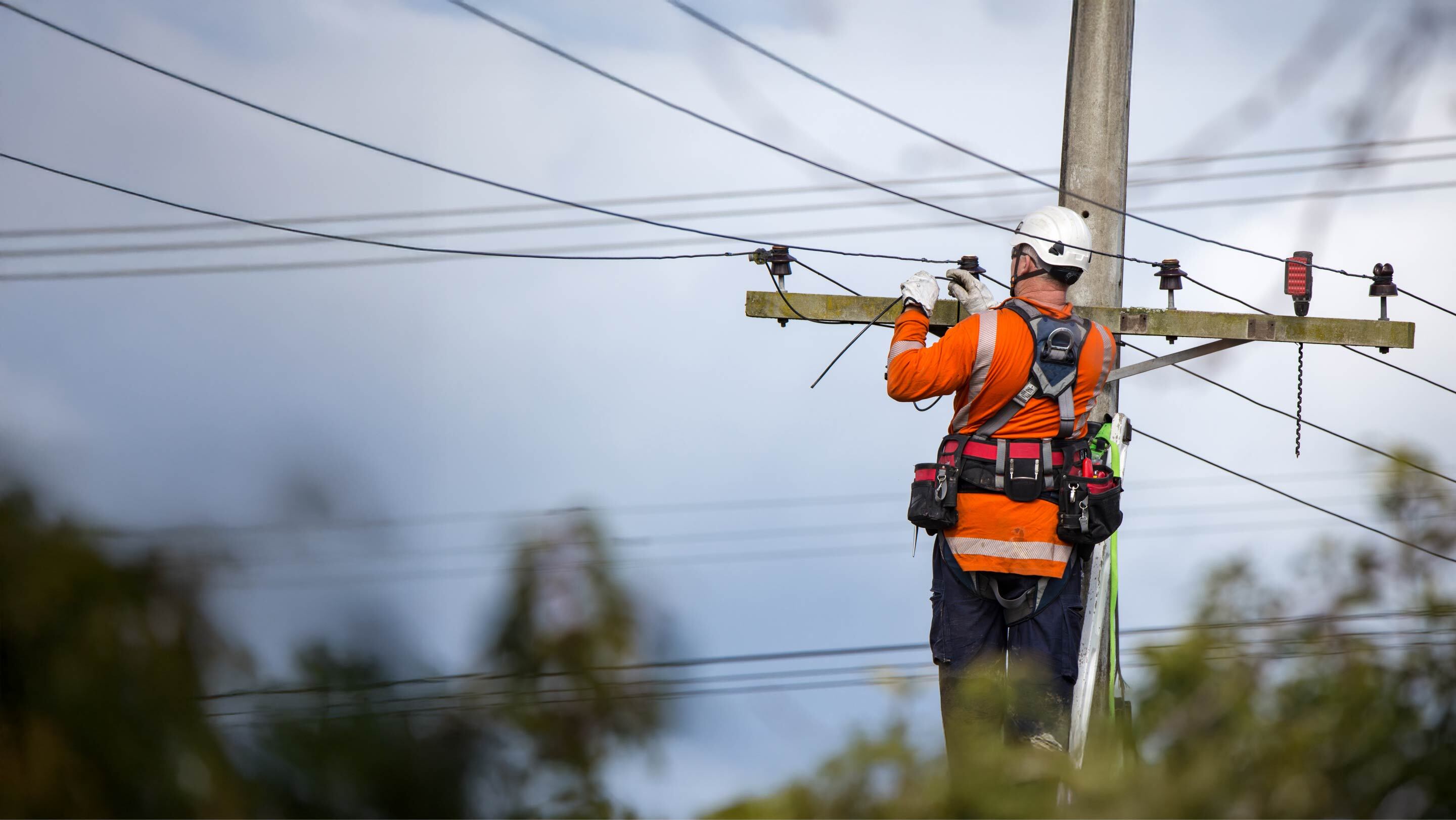 man fixing wires on electricity pole