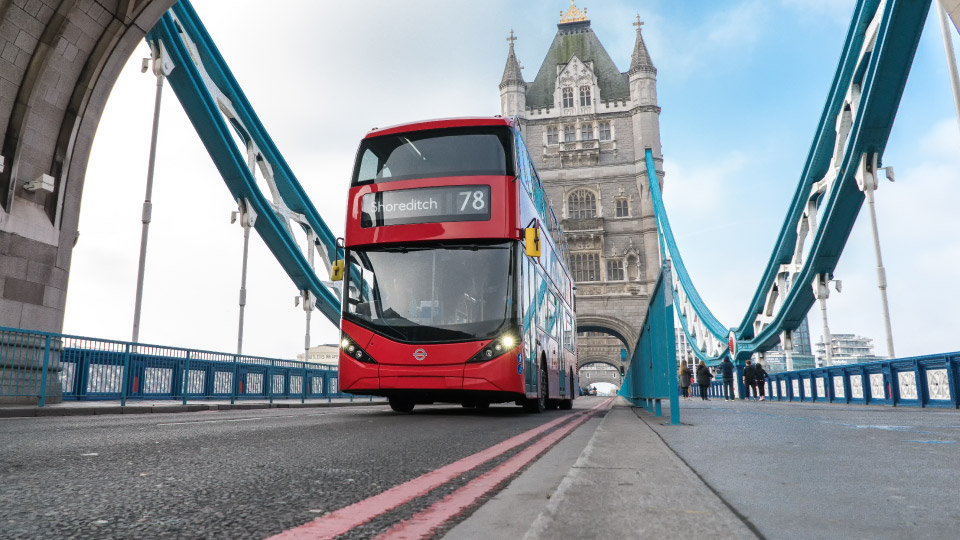 Red English bus driving over London Tower Bridge 