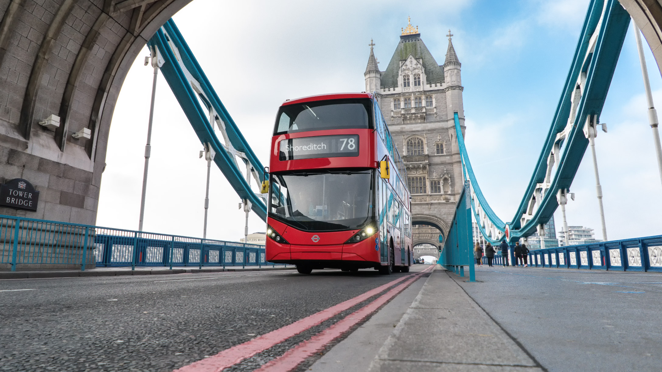 Red English bus driving over London Tower Bridge 