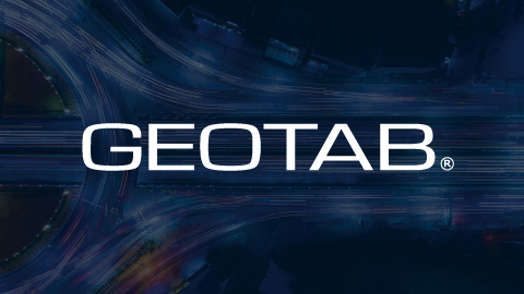Geotab logo in front of a blurred background of a lit up road during night time