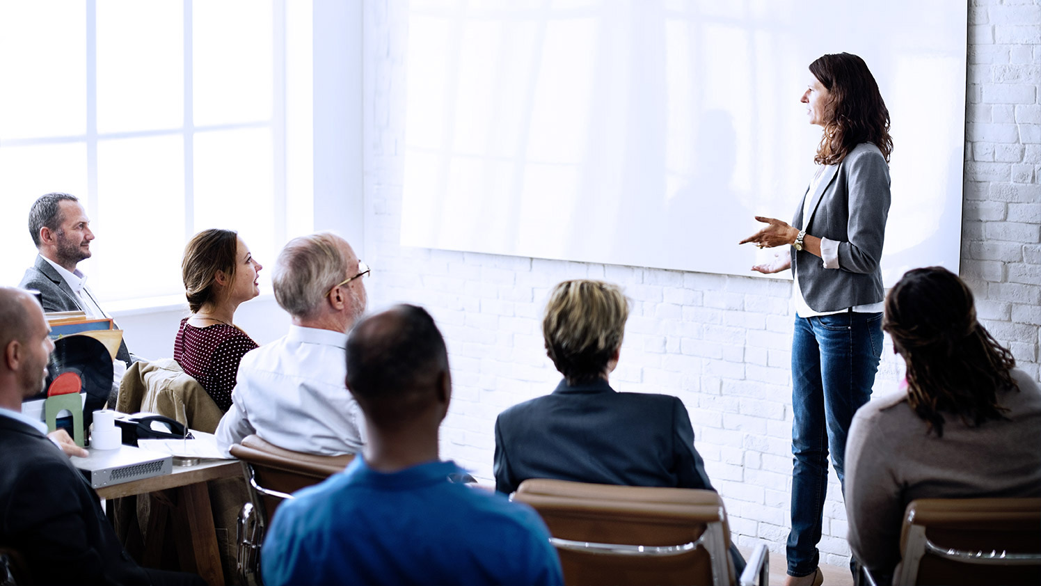 Woman speaking to a group of people in front of a whiteboard