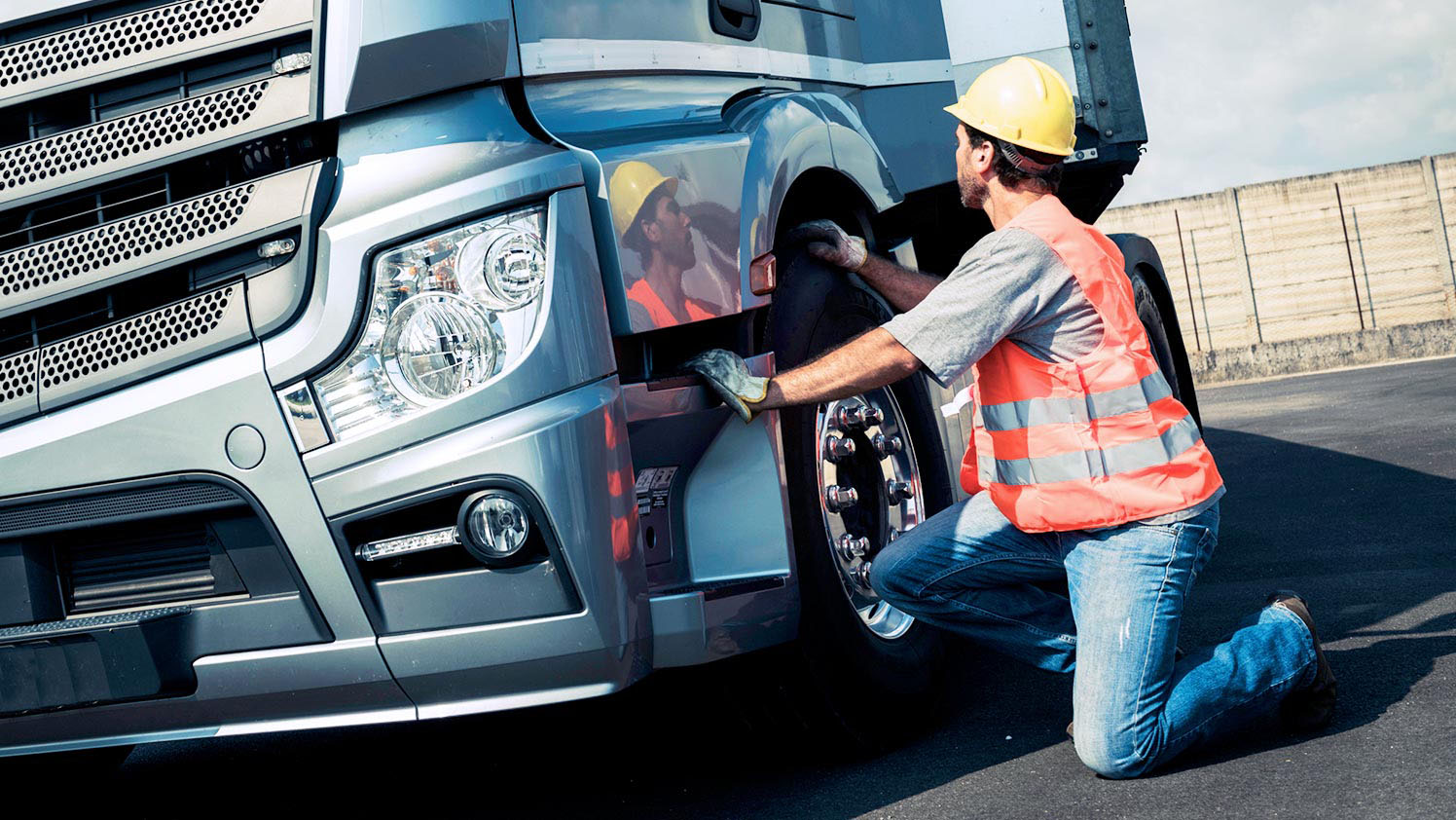 Man kneeling next to a truck checking its tire