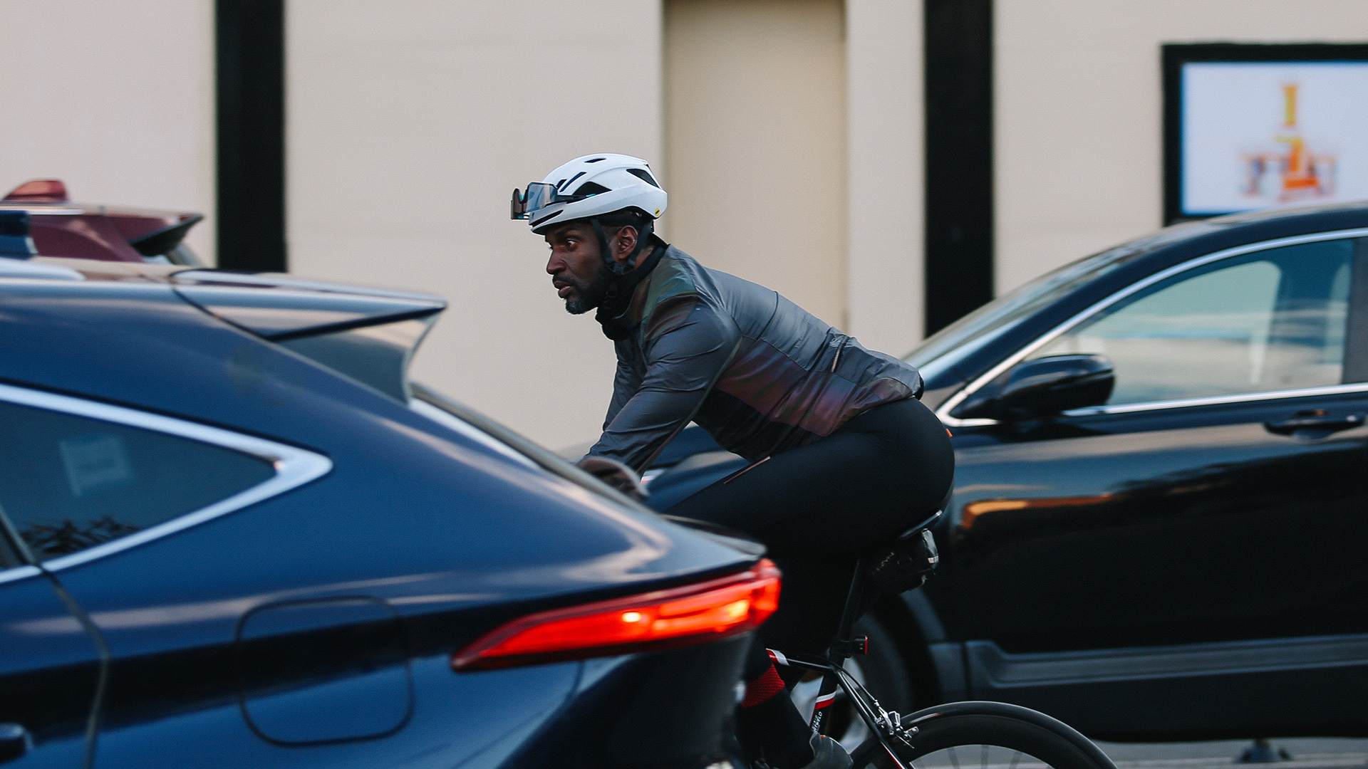 Cyclist riding between two cars in city traffic