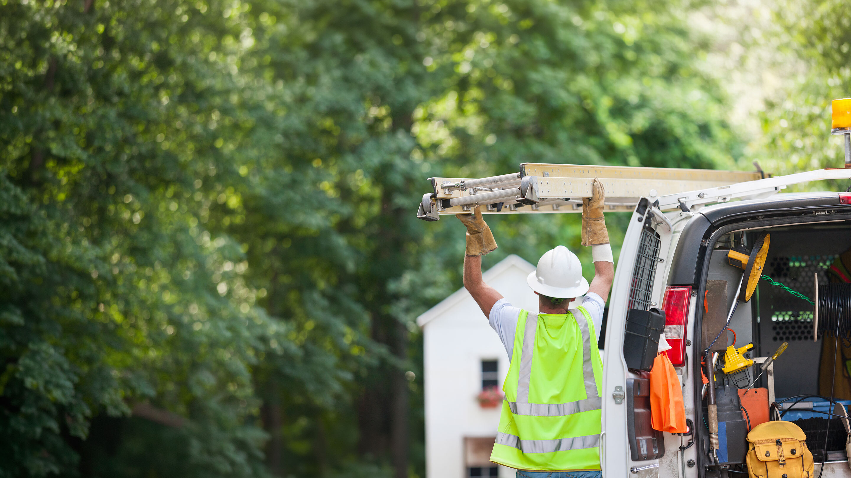 Field service technician unloading a ladder from a work van