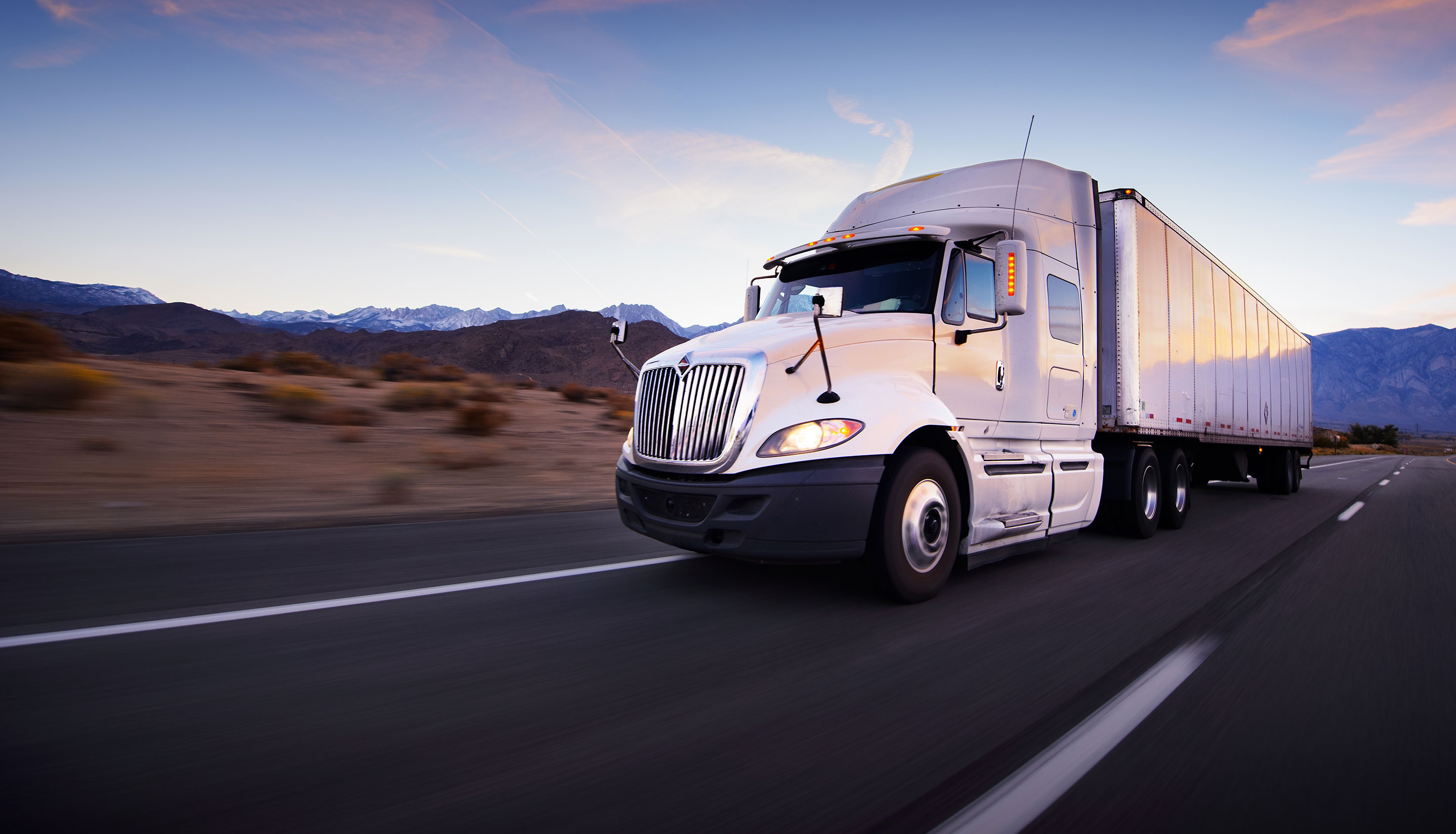 heavy truck driving on road with mountains in background